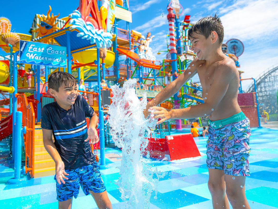 Two boys splashing at pool.