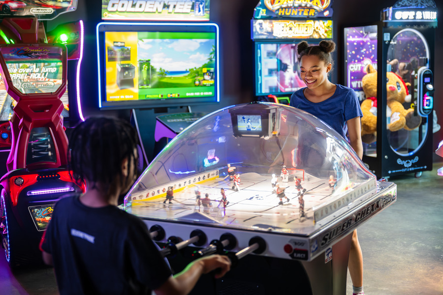 Brother and sister playing air hockey in The Bears’ Den arcade